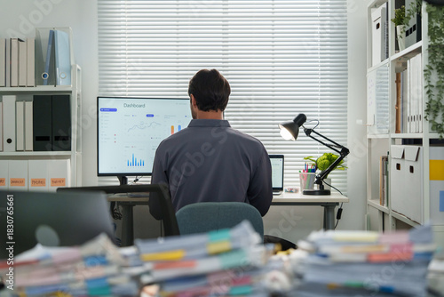 A businessman works on financial document paperwork in an overworked office while preparing an accounting report.