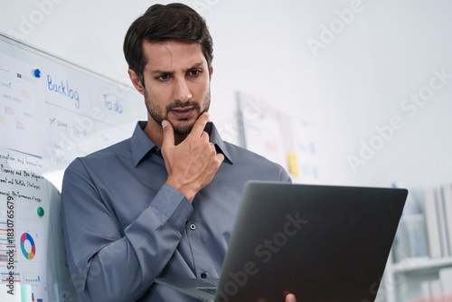 A male professional thinking and working on a financial review while planning business tasks in the office.