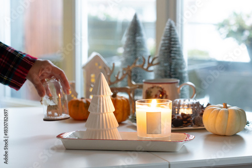 Candle light with Christmas decoration atmosphere while hand putting ornament to decorate on table.