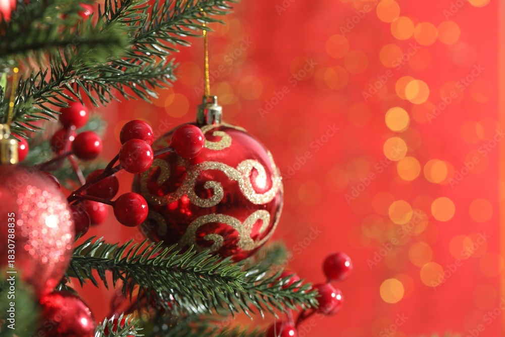 Obraz premium Beautiful ornaments on Christmas tree against red background with blurred lights, closeup and space for text. Bokeh effect
