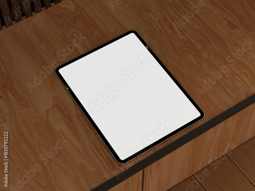 Tablet mockup with empty screen on a wooden floor near books in a modern workspace.