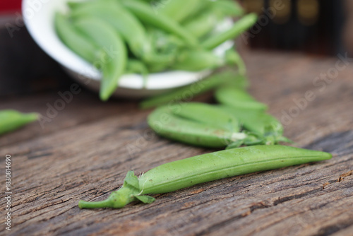  Fresh green peas in wooden bowl close-up