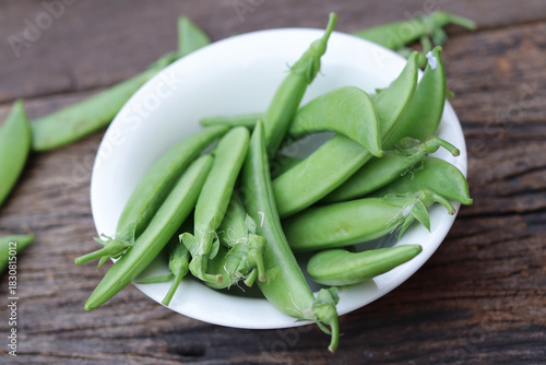 Fresh green peas in wooden bowl close-up