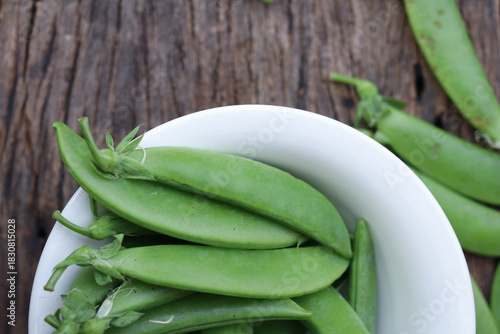  Fresh green peas in wooden bowl close-up