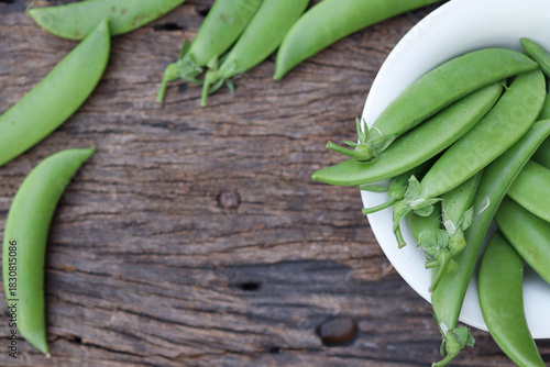 Fresh green peas in wooden bowl close-up