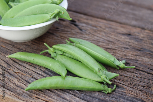Fresh green peas in wooden bowl close-up
