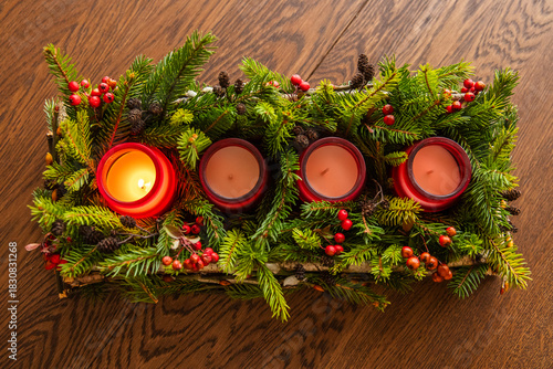 Advent wreath made of branches with one candle burning on Christmas Eve