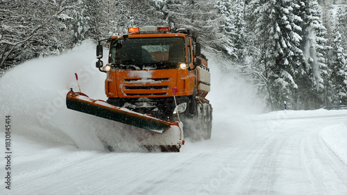 Snowplow removing snow from a winter road in a snowy forest landscape