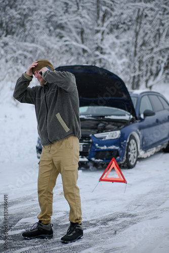 Man struggling with vehicle breakdown in winter, calling for roadside assistance