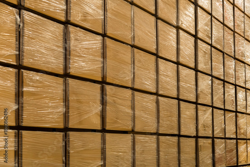Stacked cardboard boxes wrapped in plastic inside a warehouse, ready for distribution and logistics.