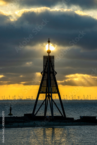 Germany. Elbe River Estuary, Cuxhaven. The silhouette of Kugelbake (historic wooden structure as a day beacon) against the rising sun located at the mouth of the Elbe River