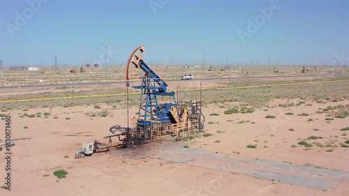 aerial view of desert oil pumpjack and surroundings, remote oil pumpjack operating in desert with maintenance equipment, industrial oil pumpjack in desert environment with service truck and wellhead