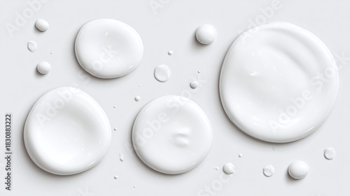 A close-up view of multiple drops of a white, creamy substance, showcasing textures and shapes.