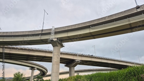 Billede på lærred Modern elevated highway bridge with concrete supports framed against a bright sky, captured in a wide architectural view