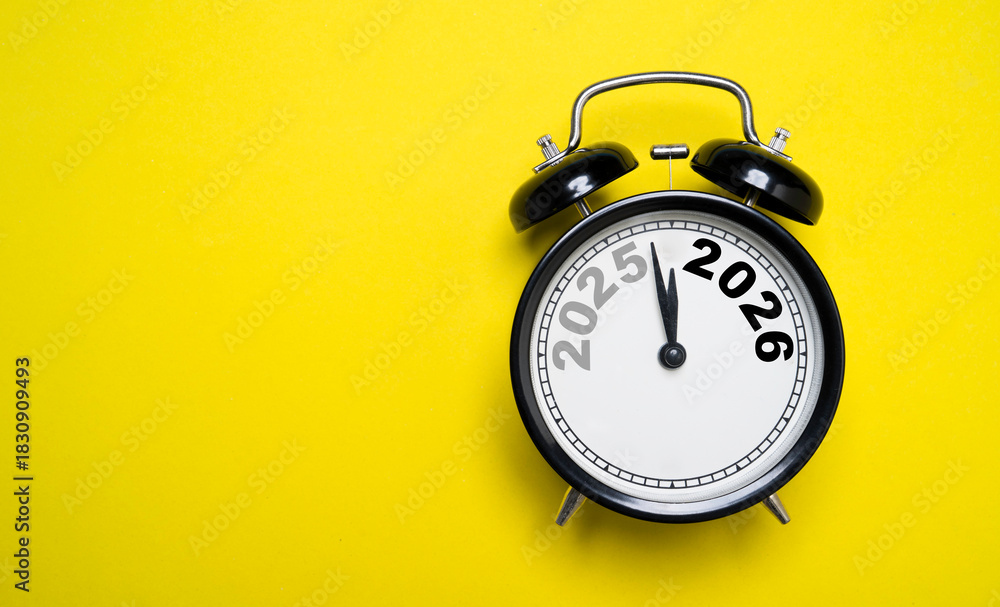 Naklejka premium Alarm clock showing 2025 turning into 2026 which symbolizing New Year countdown of time transition, future planning, celebration and year-end change on yellow background and minimal concept.