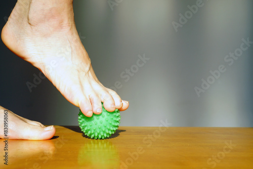 Toes gripping green massage ball demonstrating active foot muscle engagement during therapy session. Symbolizes toe strength development, intrinsic foot muscle activation, and balance training element