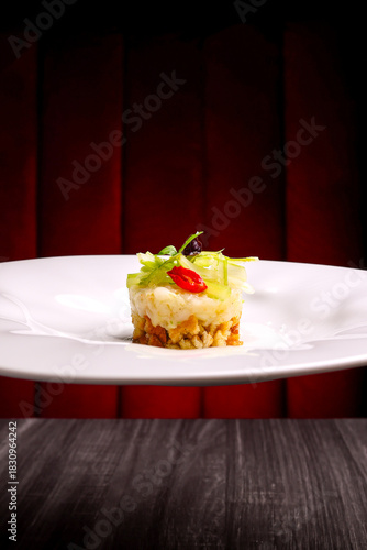 Cheescake salata tramezzata con pane croccante, baccalà mantecato, pomodoro e insalata servita in un ristorante elegante come antipasto