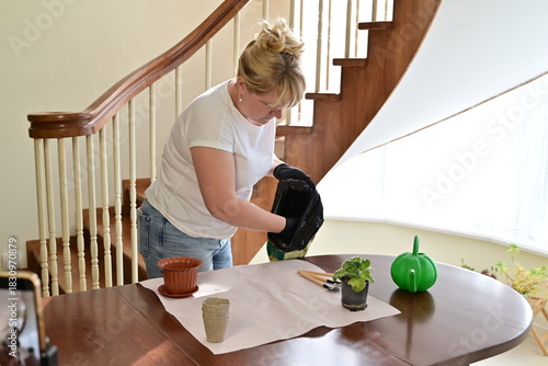 Woman using gardening tools to repot a plant at home