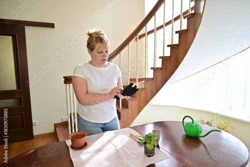 Woman using gardening tools to repot a plant at home