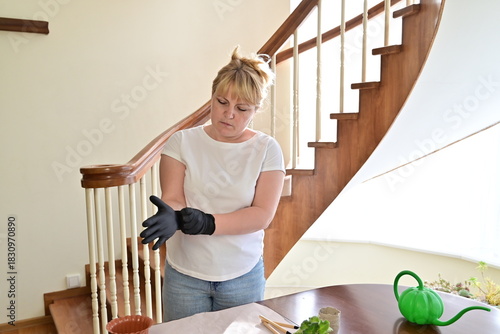 Woman using gardening tools to repot a plant at home
