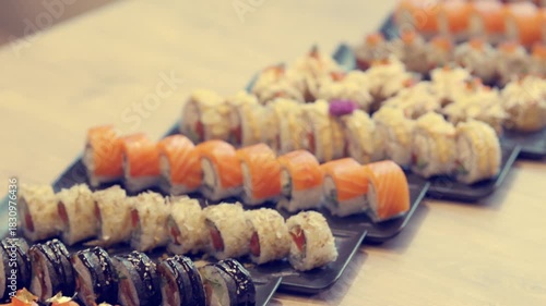 Elegant sushi rolls artfully arranged on long black ceramic plates for modern dining visuals.
