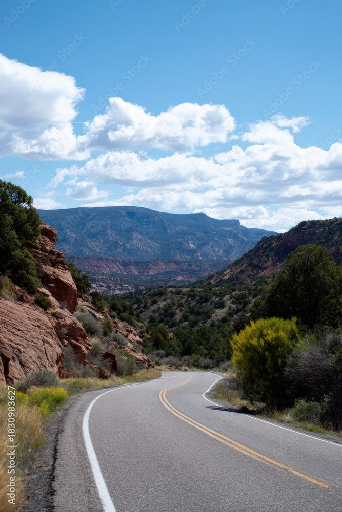 Fototapeta premium Winding road through scenic mountain landscape under blue sky