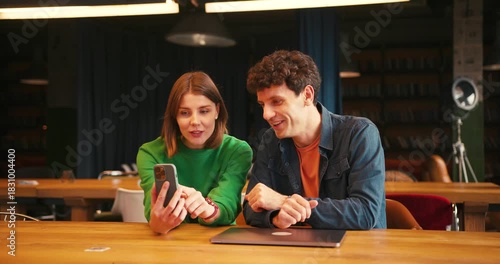 Colleagues discussing project ideas using smartphone and laptop