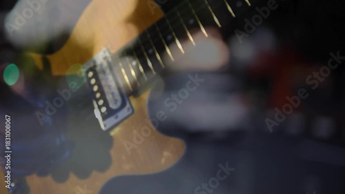 Electric guitar closeup hand entering and picking strings changing chords to play under bokeh
