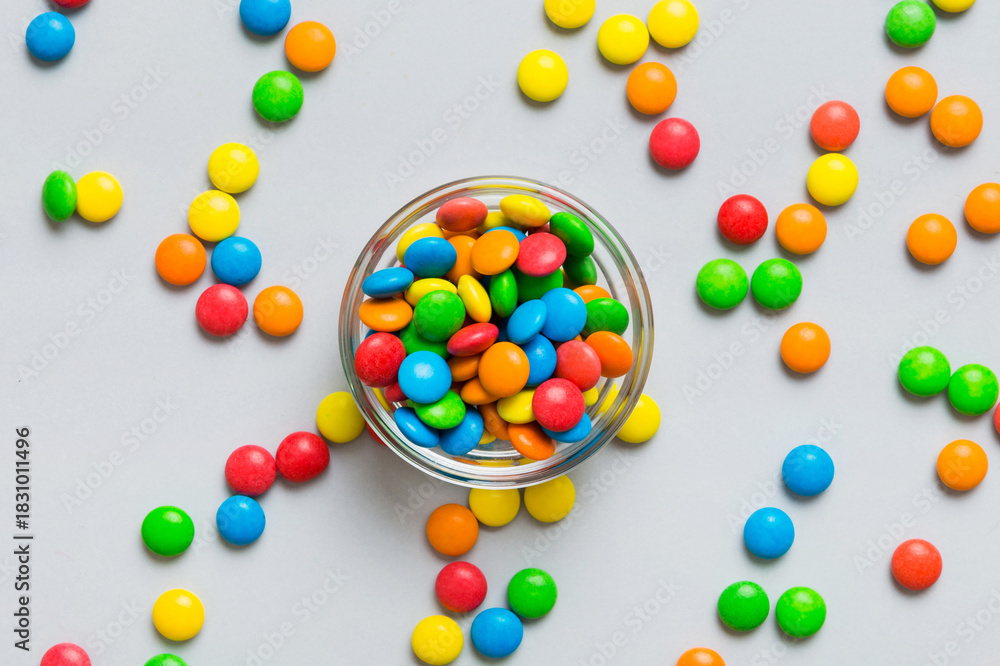 Fototapeta premium Multicolored candies in a bowl on a colored background. birthday and holiday concept. Top view with copy space