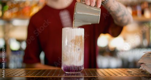 Cocktail recipe. Making beverage mix. Bartender pouring cream from clay pitcher to glass. Refreshing drink with flavored whipped top.