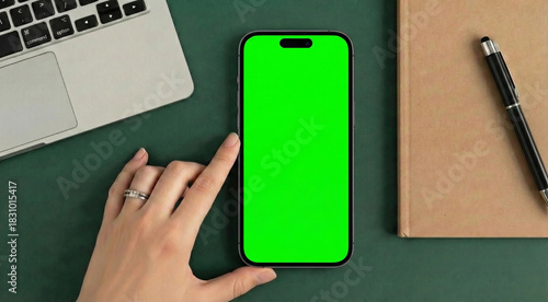Top view of woman hand using smartphone with green screen on office desk