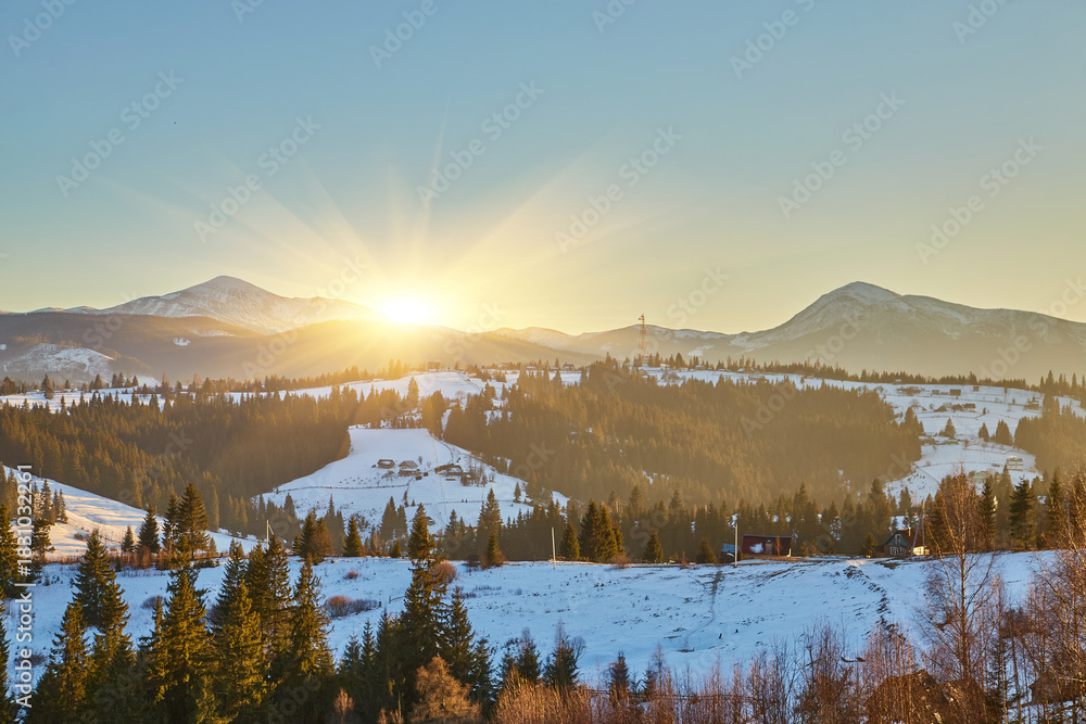 Obraz premium Winter mountain landscape with a rural village at golden hour.