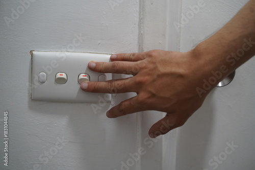 Obraz na płótnie Hand Reaching Toward Light Switch on White Wall with Three Buttons for Controlli