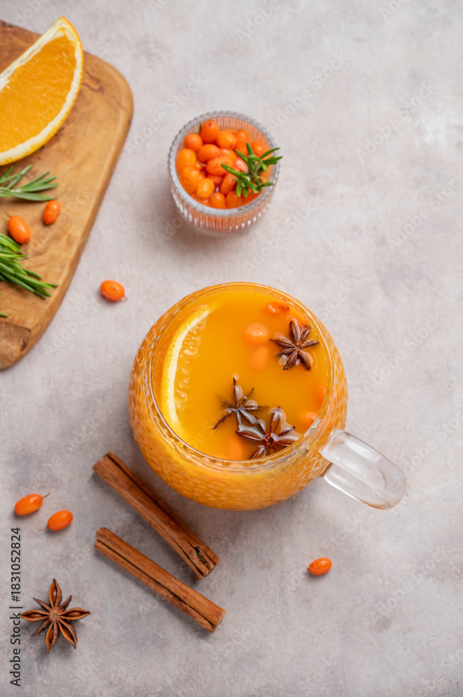 Fototapeta premium Sea buckthorn herbal tea in a cup on a light background with orange, spices and berries.