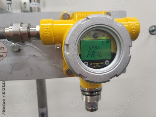 Industrial gas detector displaying error message on digital screen, mounted on metallic surface with pipes and connectors, illustrating equipment malfunction in a technical environment