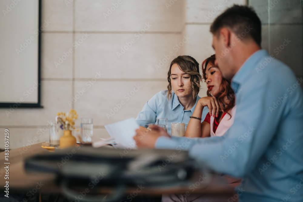 Obraz premium Three professionals review papers and discuss ideas around a table in a focused, collaborative office setting.