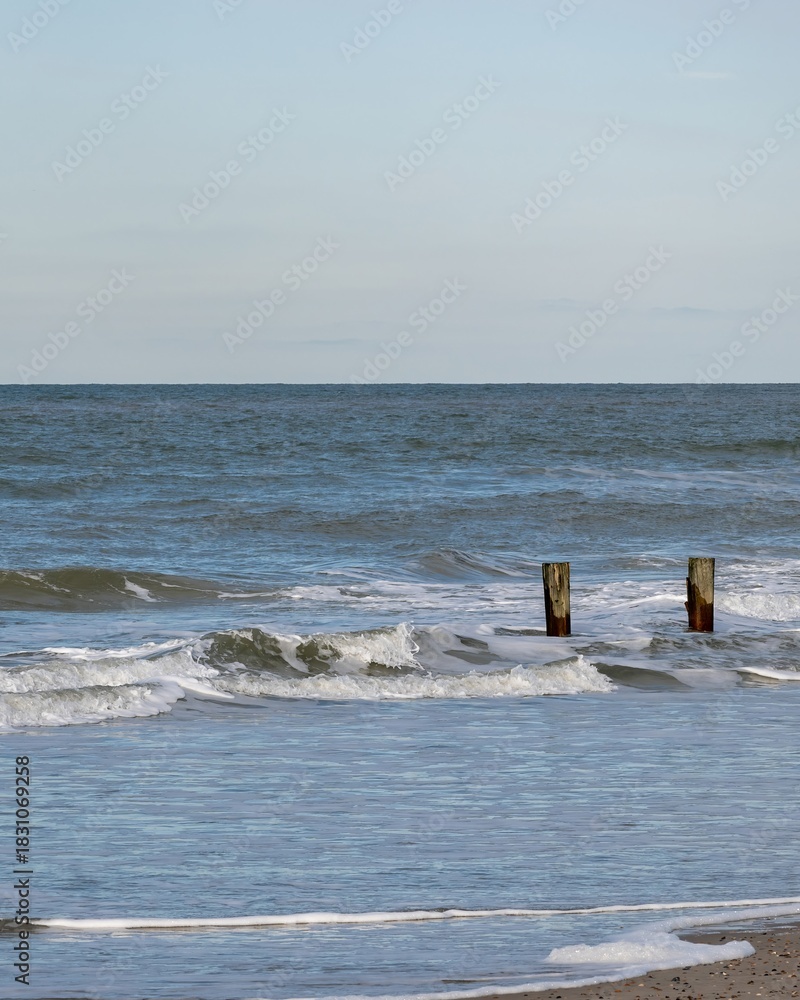 Fototapeta premium lonely beach with waves and sky in zeeland, the netherlands