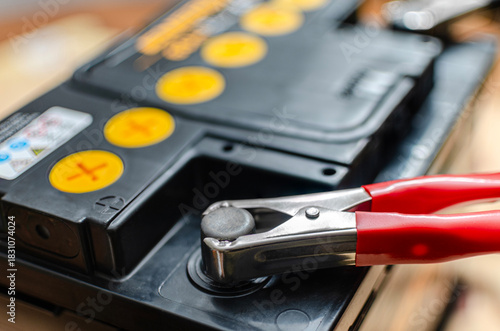 Charging a car battery with a red jumper cable clamp