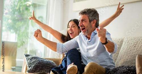 Excited couple celebrating during a sports game on TV at home