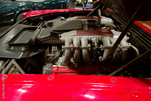 Car engine in a red sports car showing advanced engineering details and powerful design at a vehicle exhibition during the evening