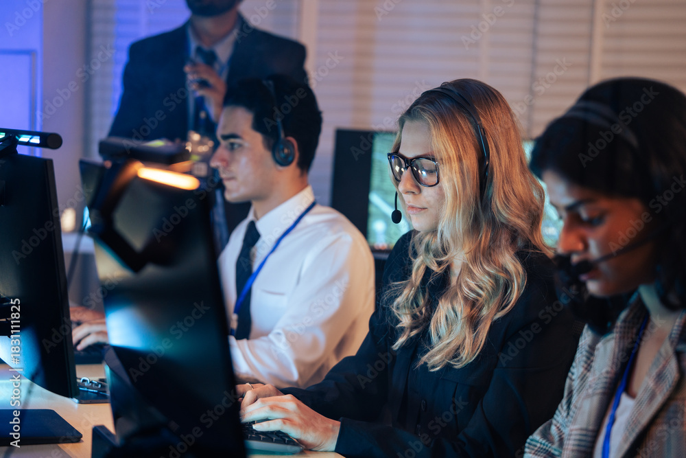 Ταπετσαρία Team of dedicated customer service agents works on computers with headsets in a dark office