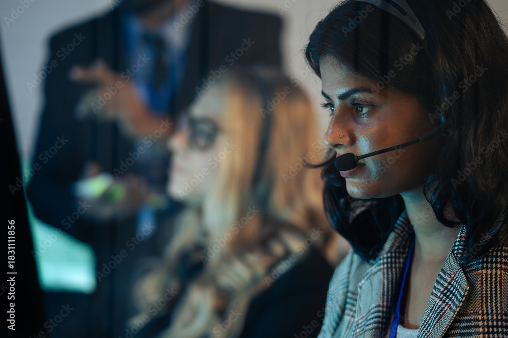 Φωτογραφία Indain call center agent or dispatcher in a headset, working urgently in a corporate operations room with colleagues