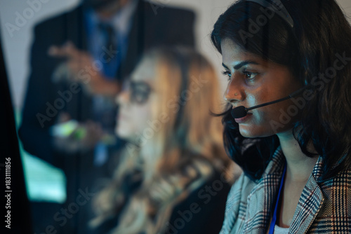 Foto Indain call center agent or dispatcher in a headset, working urgently in a corporate operations room with colleagues