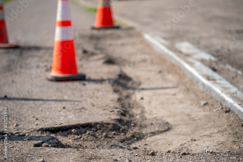 Road repair work underway with warning cones marking a damaged area in the street