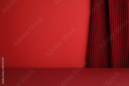 Simple, empty red studio stage with a dark red pleated curtain on the right side.