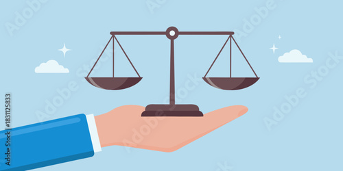 Hand holding scales of justice against a light blue sky background