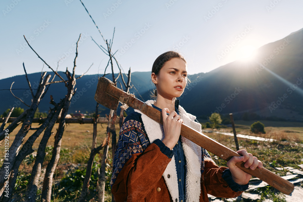Obraz premium woman plank rural mountains fence sunlight portrait of young female carrying a wooden beam on her shoulder in countryside farm outdoor scene, rustic jacket and determined expression