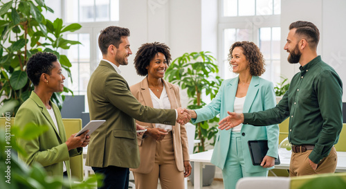 Business professionals in smart attire gather for a handshake in a modern office filled with lush green plants, collaborating and engaging in a daytime meeting