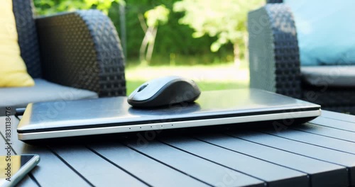 Computer technologies allow to stay in touch outside city performing work tasks. Spacious terrace contains armchairs and low wooden table with laptop and mouse