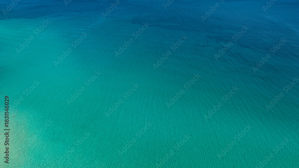 Naklejka premium Aerial view of the crystalline sea surface. The water's colors range from blue to turquoise. Ideal for backgrounds, patterns, and textures of dreamy seas.